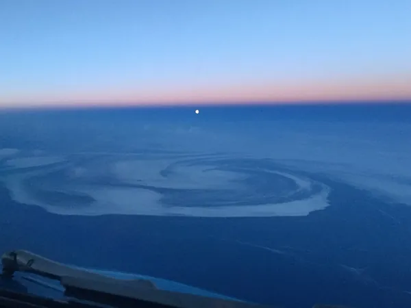 Vertigo at the edge of Greenland, a low moon hanging just above the horizon.