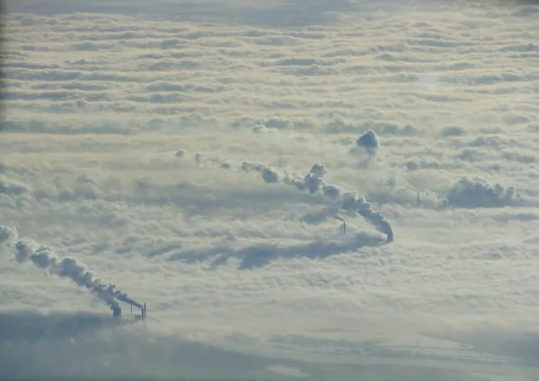 Chimneys breaking through the fog in the industrial borderland between the Netherlands and Germany.